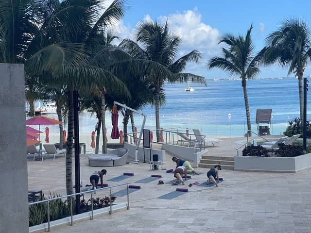 breathless-cancun-soul-beach - JJ Travel Associates - Best Travel Agents in NJ People doing yoga by the ocean at Breathless Cancun Soul